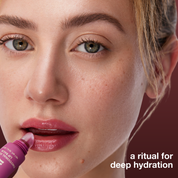 Close-up of a woman applying lip balm with text 'a ritual for deep hydration' on a dark background