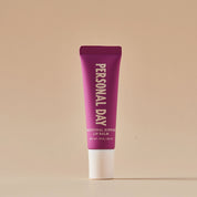 Purple lip balm tube with 'Personal Day' branding on a beige background