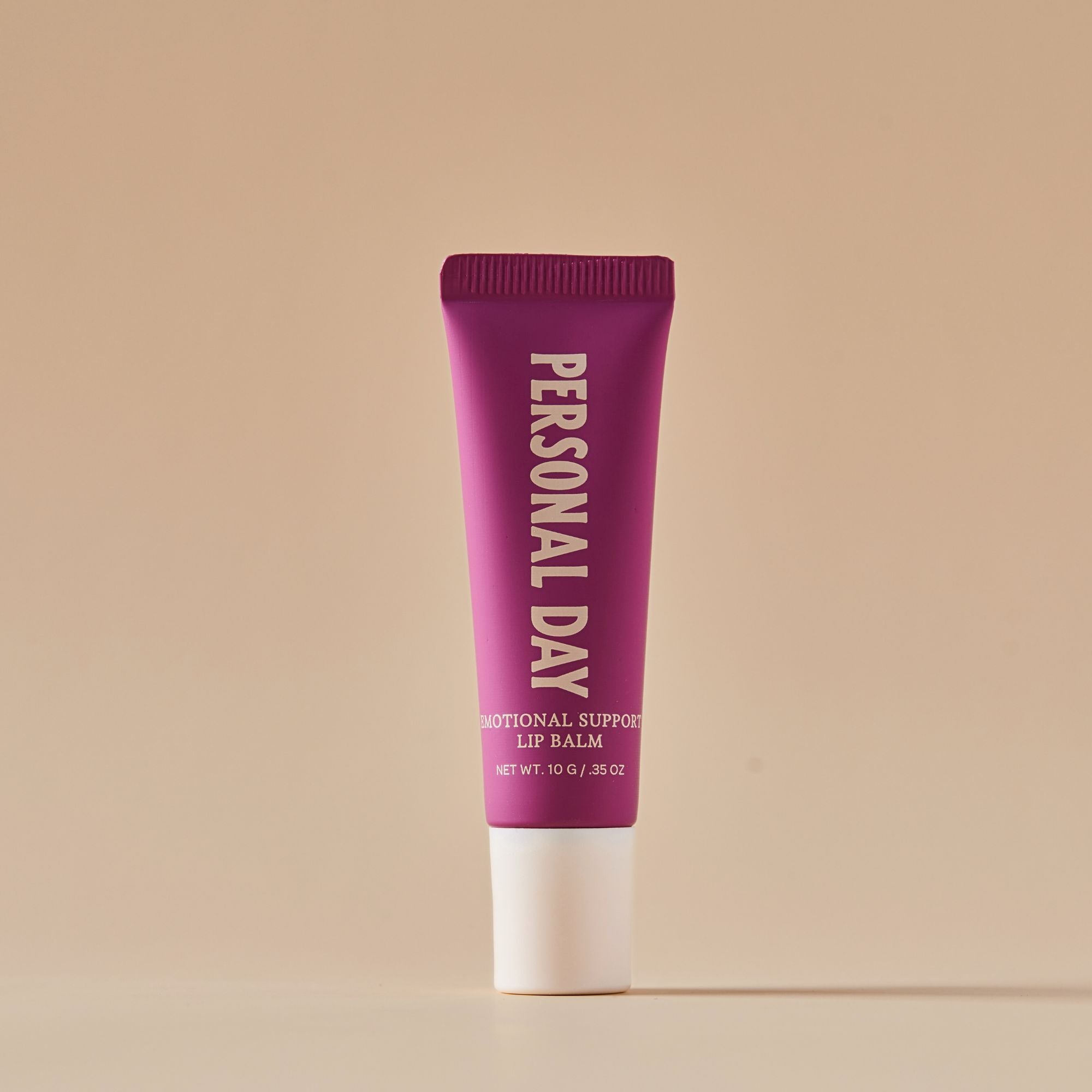 Purple lip balm tube with 'Personal Day' branding on a beige background